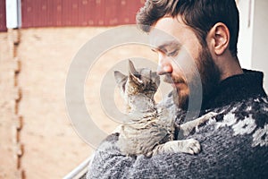 Close-up of a young man who is standing on a balcony with his cat.