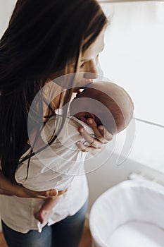 Close up young mother kissing newborn baby on forehead