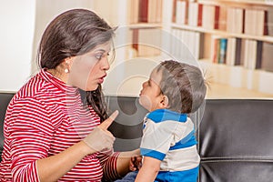 Close up of young mother talking with his little boy over a black sofa