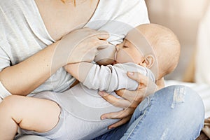 Close up of young mother who breastfeed her little kid. Touching scene of maternity love and caring. Family, motherhood