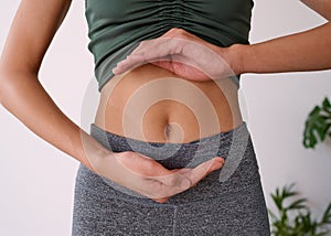 Close up of a young multi-ethnic woman& x27;s stomach cupped by her hands