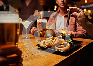 Close-up of young multiracial friends in casual clothing enjoying fast food and drinks at restaurant