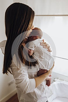 Close up young mum kissing newborn baby on forehead