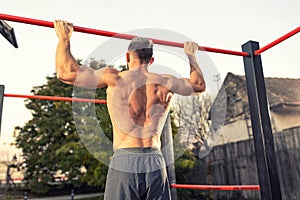 Close up of young muscular mans torso while he is doing pull ups taken from the back, close up of back muscles