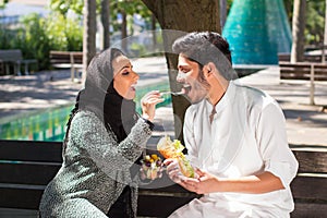 Close-up of young Muslim man and woman resting on bench