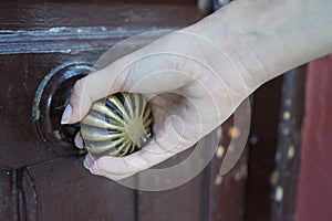 Close-up young person handle old door knob, Woman arm opening a rural hotel. Unlock retro doorway entry. Girl realtor entering photo