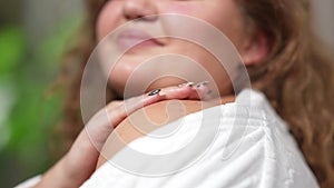 Close-up of young plus-size woman applying moisturizer on shoulder. Happy smiling Caucasian lady taking care of skin at