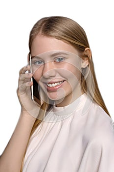 Close up of young pretty blonde girl with long hair, blue eyes smiling and using cell phone isolated on white background