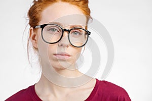 Redhead woman in glasses with hair knot looking at camera on white background