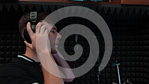Close up of young romantic pop male singer in headphones. Vocal artist singing with closed eyes. Recording at home music studio