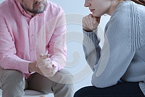 Close-up of a young sad woman sharing her grief with a psychotherapy specialist during an individual counseling meeting. photo