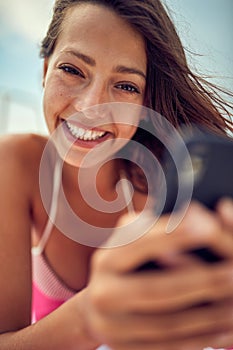 Close-up of a young sexy girl using a smartphone while posing for a photo and  enjoying a sunbath. Summer, sea, vacation