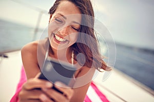 Close-up of a young sexy girl who is lying on the towel and chatting on a smartphone while enjoying a sunbath. Summer, sea,