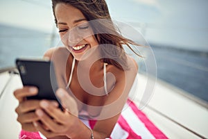 Close-up of a young sexy girl who is lying on the towel and reading message while enjoying a sunbath. Summer, sea, vacation