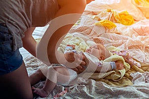 Mother swaddles and dresses a little baby girl