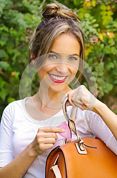 Close up of a young smiling beautiful woman keeping a menstrual cup inside of a purse. Gynecology concept, in a blurred