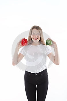 A close up of young and smiling woman who is holding red and green bell peppers. Healthy diet and vitamins. Vegetarian food.