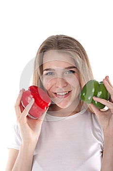 A close up of young and smiling woman who is holding red and green bell peppers. Healthy diet and vitamins. Vegetarian food.