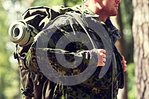 Close up of young soldier with backpack in forest