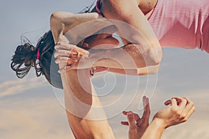 Close up of a young sporty couple practicing acroyoga exercises at sunrise or sunset.