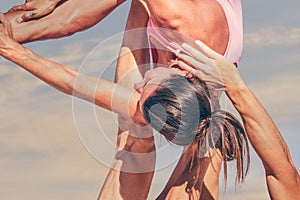 Close up of a young sporty couple practicing acroyoga exercises at sunrise or sunset.