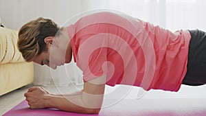 Close up of young transgender homosexual man with make up doing static plank on mat