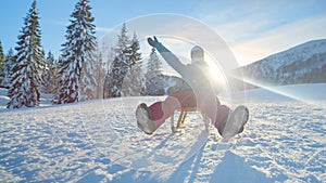 CLOSE UP: Young woman on active winter vacation goes sledding on a sunny day.