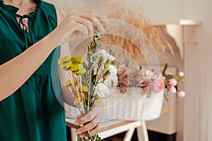 CLose up of young woman arranging floral bouquet with white carnations, eucalyptus leaves and green chrysanthemum. Florist couse. photo