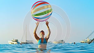 CLOSE UP: Young woman in bikini plays with huge inflatable ball on sunny evening