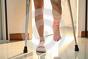 Close-up Young woman broken leg with crutches walking out from the toilet