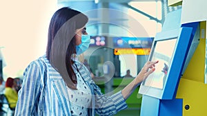 Close-up, a young woman checks in on self check-in kiosk at the airport. air travel opening after coronavirus pandemic.