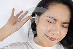 Close up young woman cleaning ears, using cotton bud after shower, feeling pain