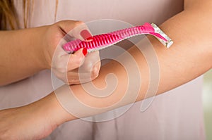 Close up of a young woman cleaning a shaver with a brush, with a blurred woman behind