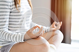 Close up of young woman doing yoga meditating on the bed at home after waking up in the morning