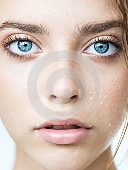 Beautiful young woman with clean perfect skin and water moisture drops touching face