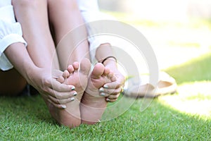 Close-up of young woman feeling pain in her foot on the grass, H