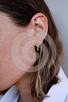 Close-up of young woman with golden earring. Beauty model girl in jewellery, perfect face closeup.