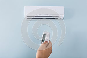 Woman Operating Air Conditioner With Remote Control