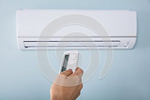 Woman Operating Air Conditioner With Remote Control