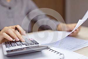 Close up young woman hand using calculator counting making Calculate the cost of checking documents income and tax notes accountin