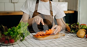 Close up young woman hands preparing a healthy salad. Cutting vegetables tomatoes on a cutting board on the home