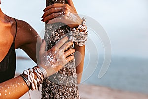 Close up of young woman hands wearing boho accessories made of cowry shells