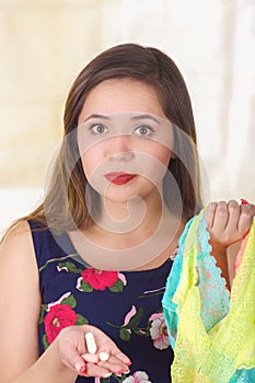 Close up of a young woman, holding an assorted colorful underwears and a soft gelatin vaginal tablet or suppository