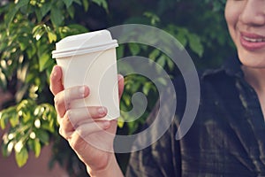 Close-up of young woman holding coffee to take away at early morning