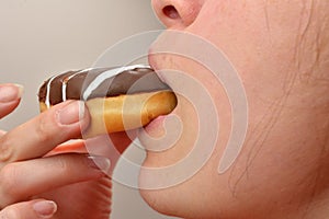 Close up of a young woman holding a delicious doughnut with choc