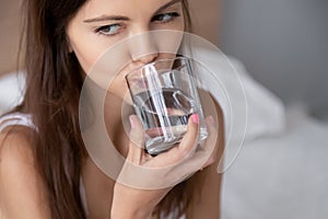 Close up young woman holding glass drinking water