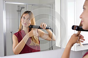 Vista ravvicinata di giovane donna latino vapore piastra per capelli sul stile capelli Specchio sul il bagno 