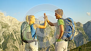 CLOSE UP: Young woman and man high five after hiking up to the mountaintop.