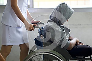 close up young woman nurse push wheelchair for man patient in hospital