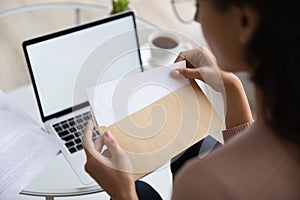 Close up young woman opening envelope with letter.